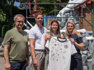 Ann-Kathrin Mack et Nia Künzer tiennent ensemble un maillot signé de l'équipe nationale. À leurs côtés : Christian Wück et Nicolas Mack.