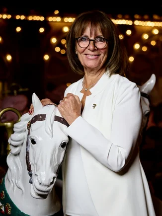Marianne Mack stands next to a wooden horse from the historic Eden Palladium carousel.