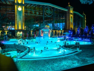 The heated outdoor pool Frigg Tempel at Rulantica water world in the dark. Guests splash around happily as the lighting bathes the pool in a magical atmosphere.