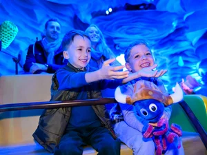 Children sit together with their parents and a Snorri soft toy in the Snorri Touren attraction at Europa-Park.