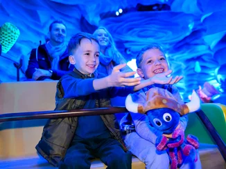 Children sit together with their parents and a Snorri soft toy in the Snorri Touren attraction at Europa-Park.