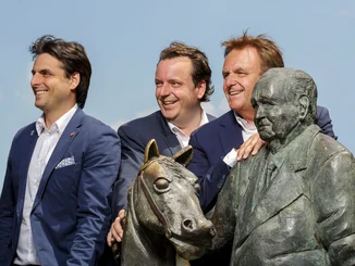 Franz-Mack-Statue mit Roland, Michael und Thomas Mack an einem sonnigen Tag unter blauem Himmel.