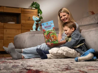 A mother sits next to her little son and reads to him from the Madame Freudenreich children's book.