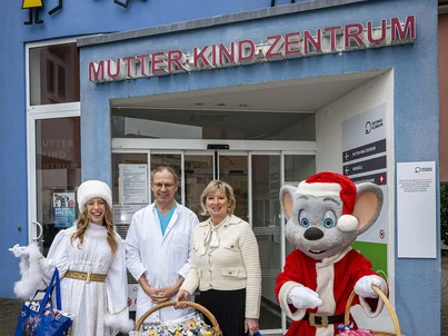 Mauritia Mack, Ed Euromaus and a Christmas angel distribute gifts at a mother-and-child centre.