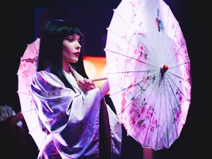 A dancer from the Europa-Park Dinner-Show wearing a striking costume and carrying an umbrella.