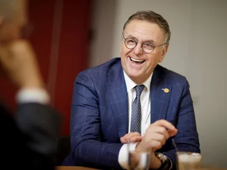 Roland Mack sits at a conference table and smiles.