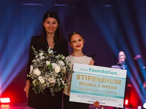 Katja Mack presents a girl with a cheque for a scholarship from the Talent Foundation e.V. association