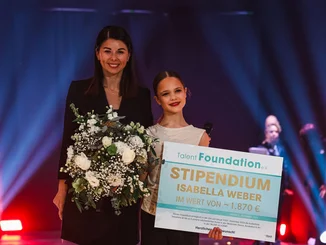 Katja Mack presents a girl with a cheque for a scholarship from the Talent Foundation e.V. association