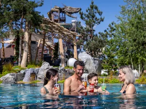 Family refreshes themselves with a delicious drink at the Svømme-Bar in the outdoor pool Svømmepøl in Rulantica.