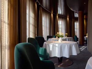 An interior view of the Ammolite – House of Light restaurant at the ‘Bell Rock’ themed hotel. Each laid table features a white vase of flowers. The atmosphere is very modern and elegant.