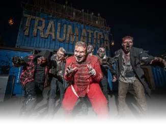 Six zombies énervés de Traumatica Six zombies énervés avec des habits déchirés se tiennent devant l’entrée qui mène au site de Traumatica. Au-dessus, on voit l’inscription « Traumatica » sur un container.