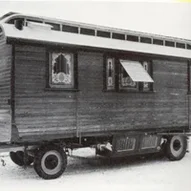 Historischer Holzwohnwagen mit verzierten Fenstern.
