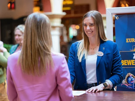 Employee of the Europa-Park Resort recruitment team talking to a potential applicant at an information stand.
