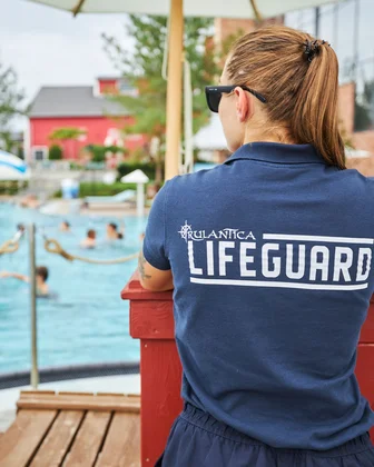 Rettungsschwimmerin mit Sonnenbrille und Lifeguard-Shirt beobachtet Badebereich in Rulantica.