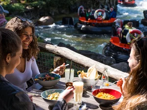 A group of friends enjoy fresh food at the restaurant SPICES in Europa-Park with a view of Fjord Rafting.