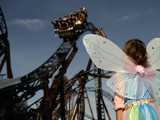 Une petite fille déguisée en fée à Europa-Park. Elle regarde le grand huit Voltron Nevera powered by Rimac.