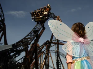 Une petite fille déguisée en fée à Europa-Park. Elle regarde le grand huit Voltron Nevera powered by Rimac.