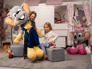 Deux enfants jouent dans leur chambre avec de grandes Euromaus en peluche.