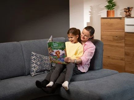 Une mère lit à sa fille un livre de la série de livres pour enfants Fina & les Yomis.