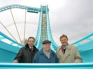 Jürgen, Franz und Roland Mack stehen auf der Atlantica SuperSplash im Winter zwischen türkisfarbenen Schienen.