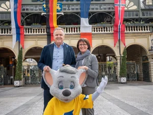Roland Mack stands with his wife Marianne Mack and Ed Euromaus in front of the main entrance to Europa-Park.