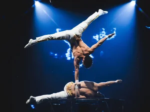 An acrobat from the Europa-Park Dinner-Show balances on one hand, supported by his partner's hand.