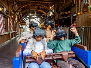 Passengers wearing VR headsets sit on the Alpenexpress Coastiality attraction.