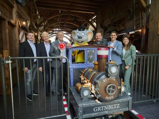 Frederik, Jürgen, Roland, Michael, Thomas und Ann-Kathrin Mack zusammen mit Ed Euromaus neben einem Zug des Alpenexpress.