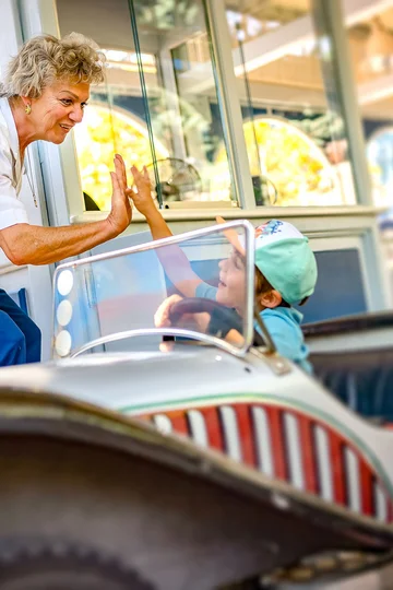 Mitarbeiterin an einer Attraktion gibt einem kleinen Jungen ein "High-Five".