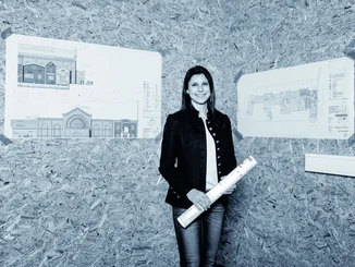 Ann-Kathrin Mack vor den Bauplänen für das 4-Sterne Superior Erlebnishotel "Krønasår".