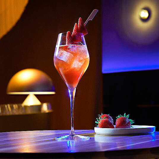 Welcome Drink Eatrenalin Hohes, gewölbtes Champagnerglas mit einem lecker-beerigen Welcome-Drink bei Eatrenalin Late Night.