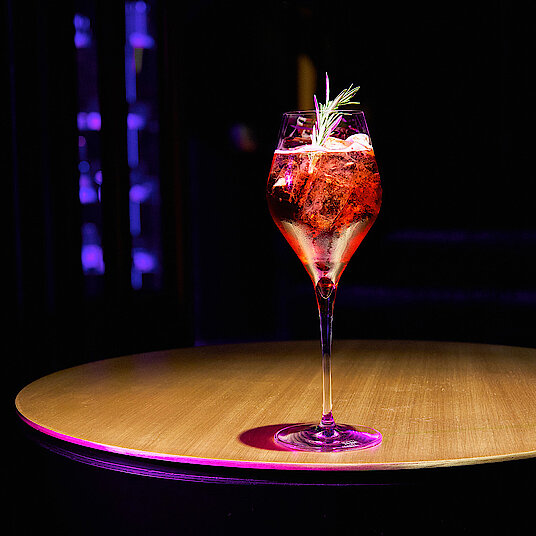 Cocktail Lounge Eatrenalin Ein hohes, gewölbtes Champagnerglas mit einem lecker-spritzigen Aperitif in der Lounge von Eatrenalin Late Night.