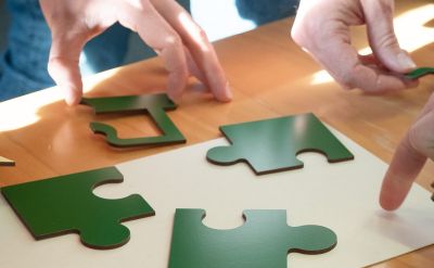 Several people work together to solve a green puzzle on a table in the Confertainment Center at Europa-Park.