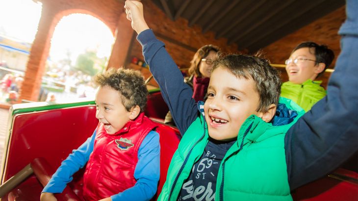 Vier lachende Kinder im Dancing Dingie im Irischen Themenbereich des Europa-Park, ein Junge hebt die Arme in die Luft.