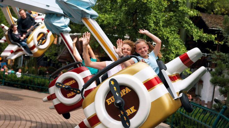 Mutter und Tochter im Jungfrau-Gletscherflieger im Schweizer Themenbereich des Europa-Park. Sie heben die Hände freudig in die Luft.