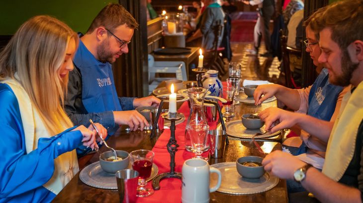Vier personen eten aan de tafel van het Alemannische Rittermahl in Slot Balthasar.
