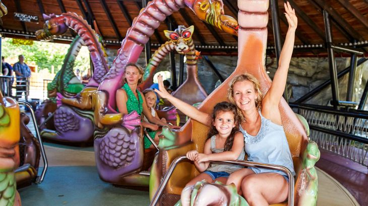 Una madre con la figlia sulla giostra Spinning Dragons.