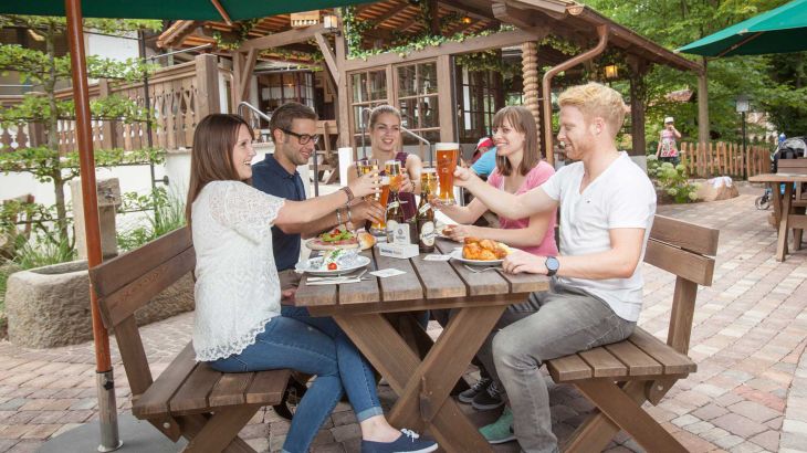 Quattro persone brindano insieme mentre mangiano in un ristorante tradizionale austriaco all’Europa-Park.