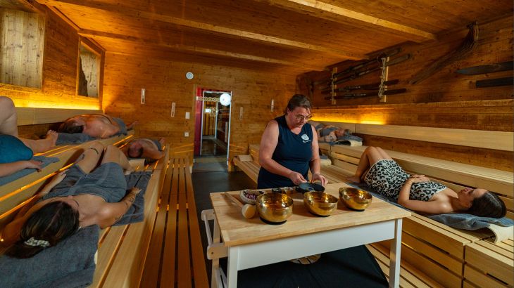 Plusieurs personnes se détendent dans le sauna « lille » dans l’espace détente et sauna exclusif Hyggedal à Rulantica.