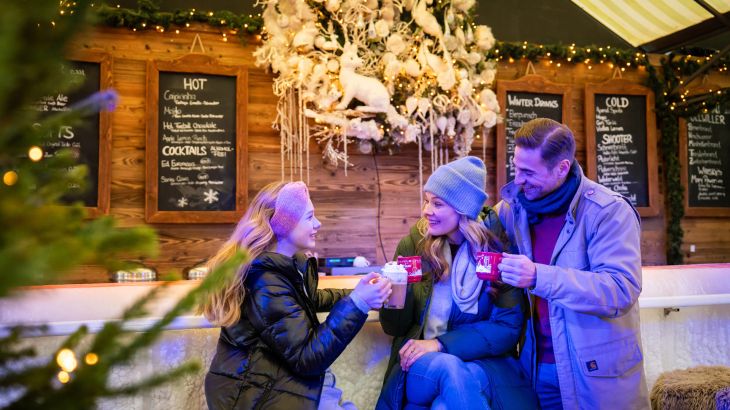 Un couple et un enfant trinquent avec des boissons chaudes au sein de l’Ice Bar dans le quartier espagnol d’Europa-Park.