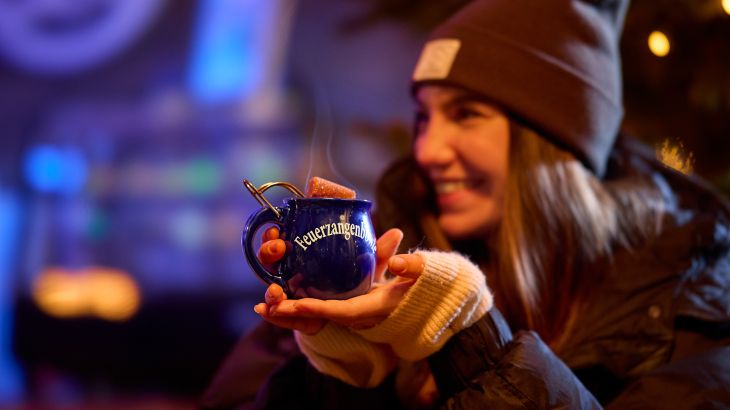 Une femme assise au sein de l’Ice Bar dans le quartier espagnol d’Europa-Park tient un punch flambé vers la caméra.