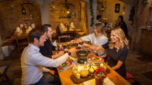Four people are enjoying fondue together at the Europa-Park Resort and raising their glasses to each other.