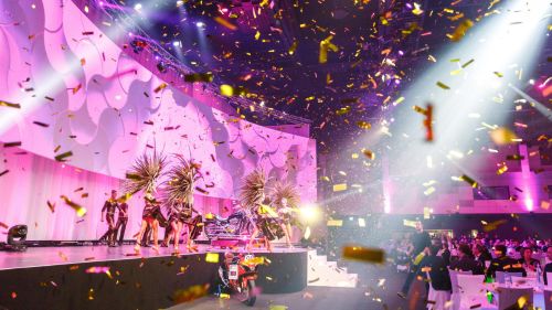 Een podiumshow met gouden confetti en roze licht in het Confertainment Center van Europa‑Park.