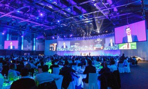 Een lezing op een groot podium met meerdere LED‑schermen in het Confertainment Center van het Europa‑Park Resort.